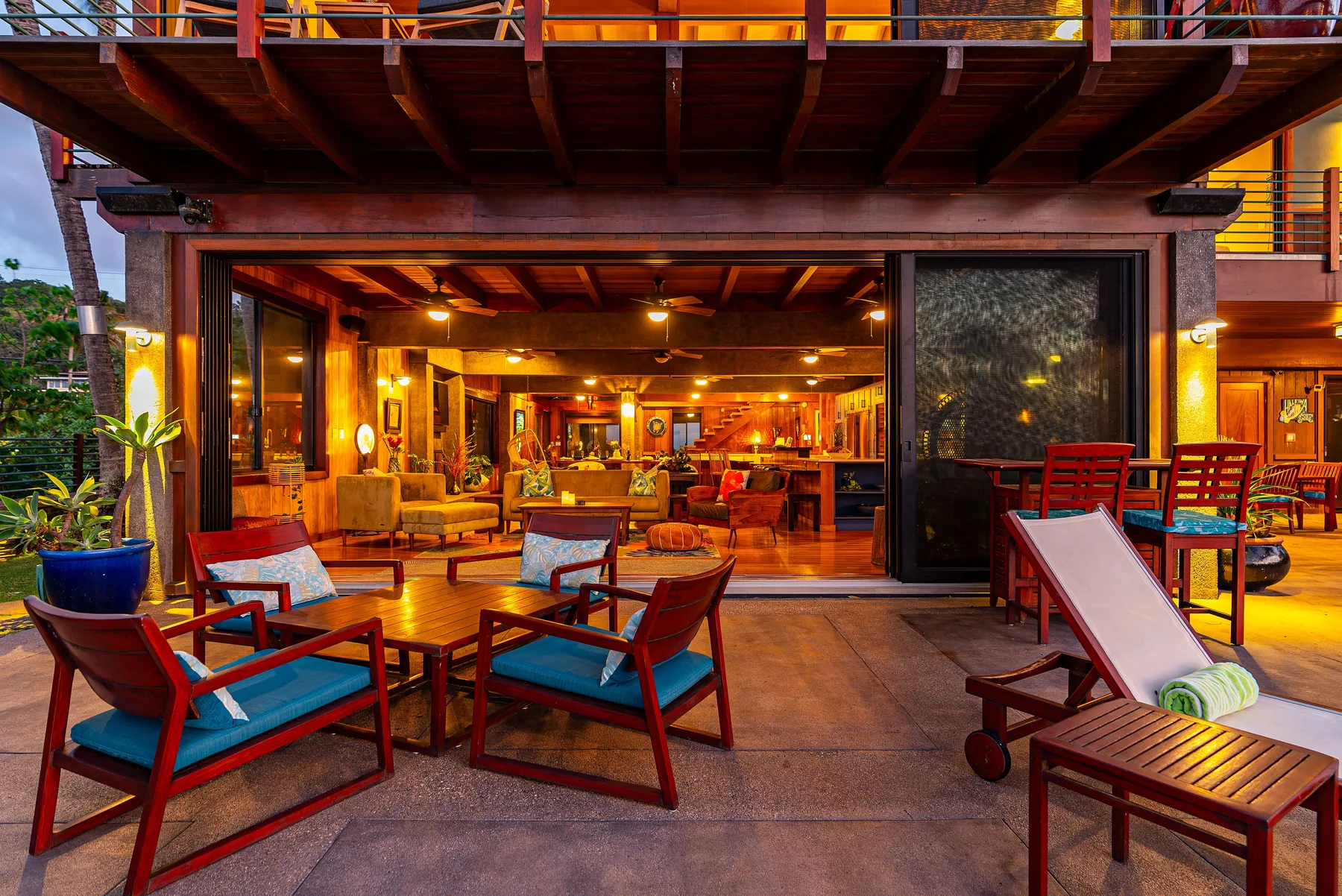 Un salón abierto al exterior con asientos de madera y un interior cálidamente iluminado.