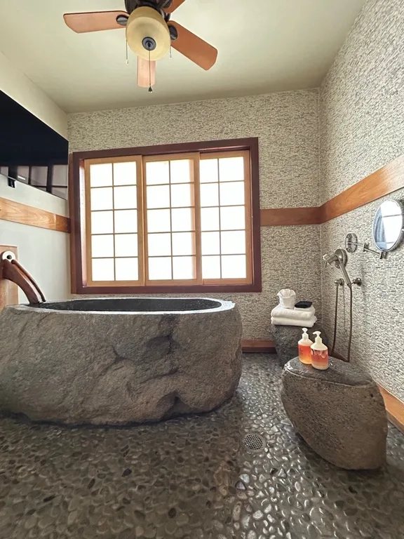 Un baño con una gran bañera de piedra bajo una ventana.
