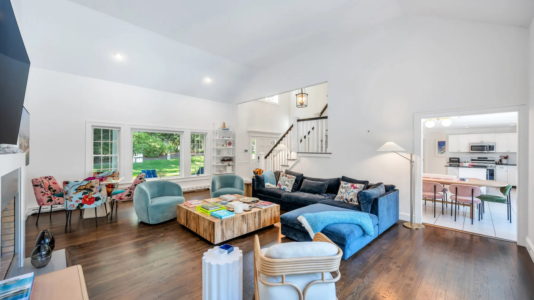 A bright living room with blue seating and a coffee table beside large windows.