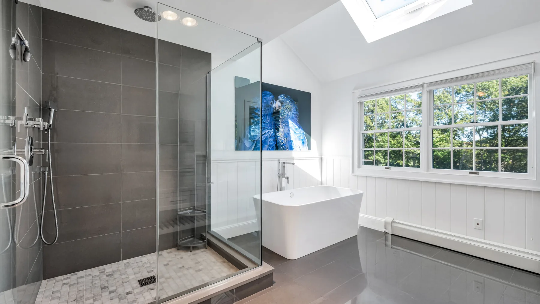A bright bathroom with a glass shower, freestanding tub, and large windows.