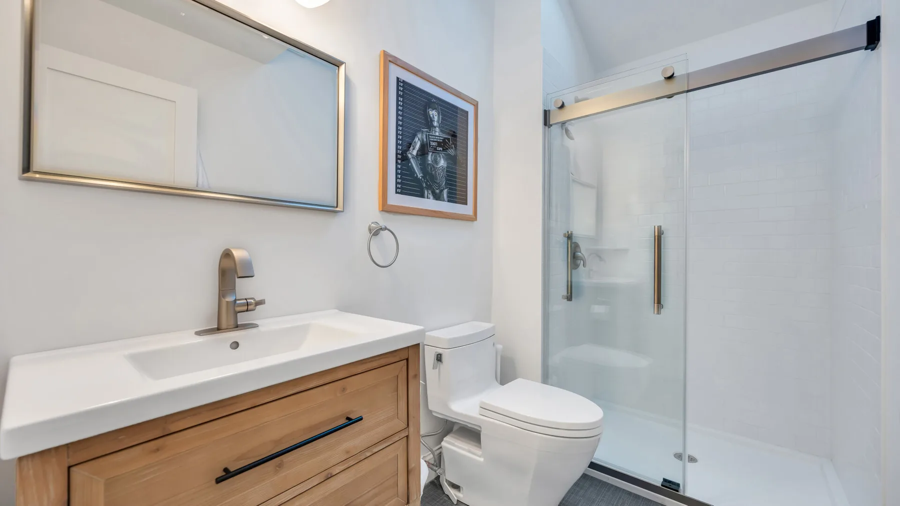 A bathroom with a sink vanity, toilet, and glass shower.