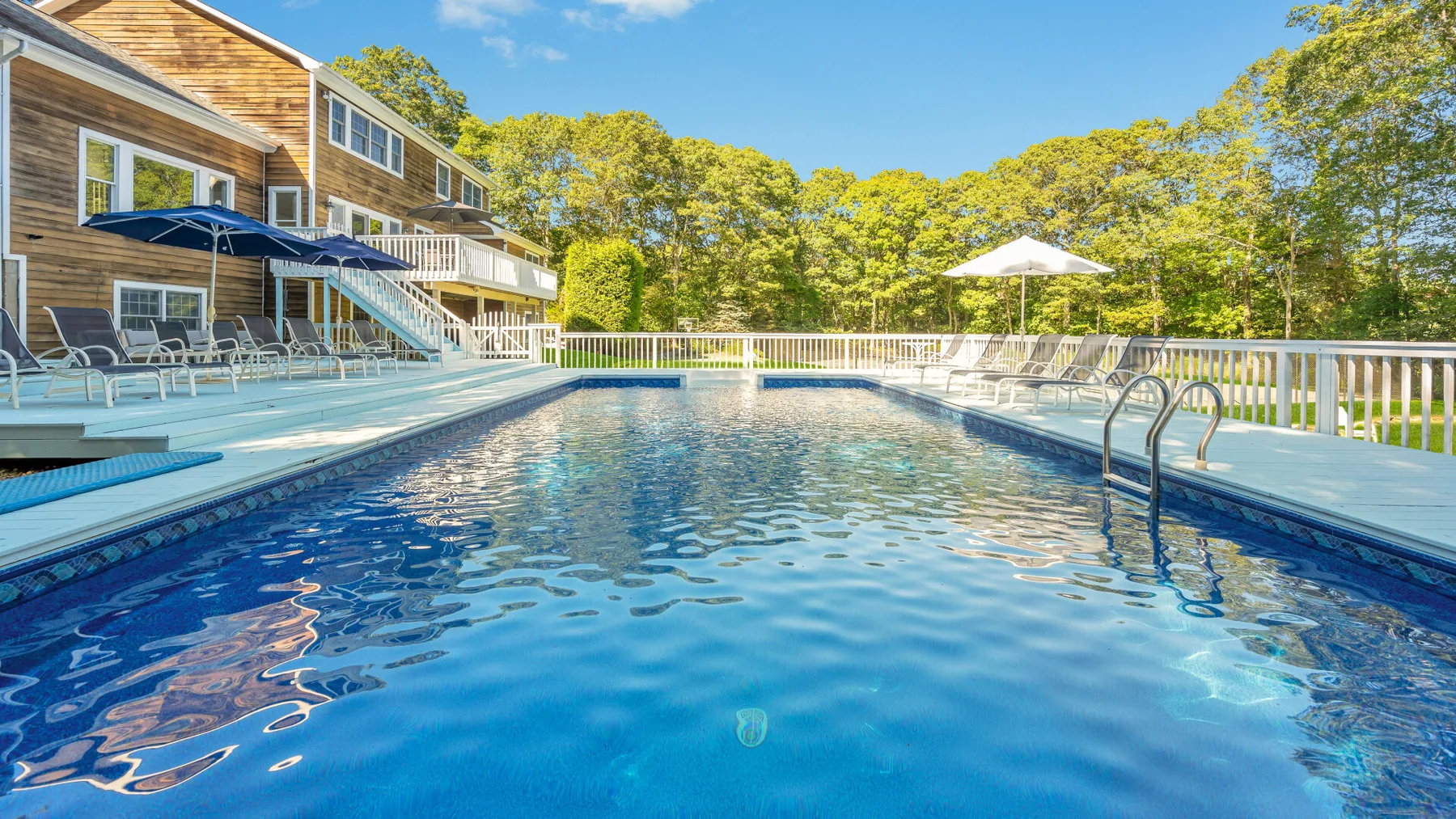 An outdoor swimming pool beside a wooden building and surrounding trees.