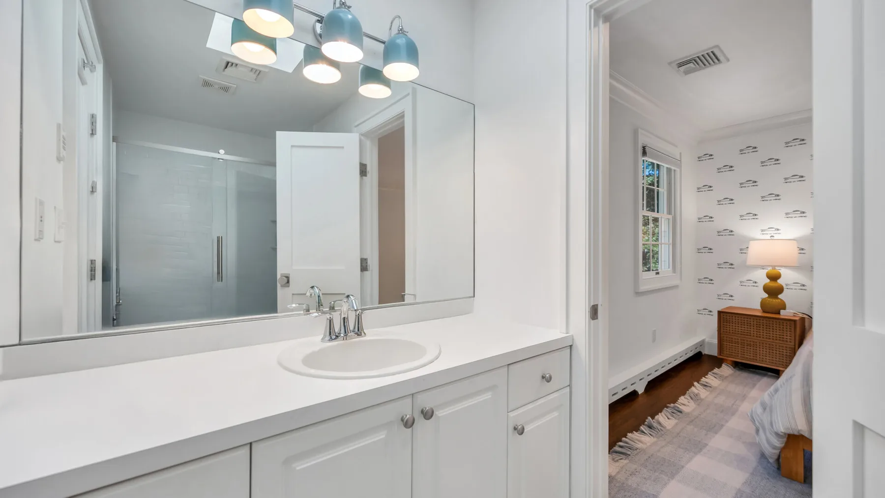 A bright bathroom vanity with a sink and large mirror.