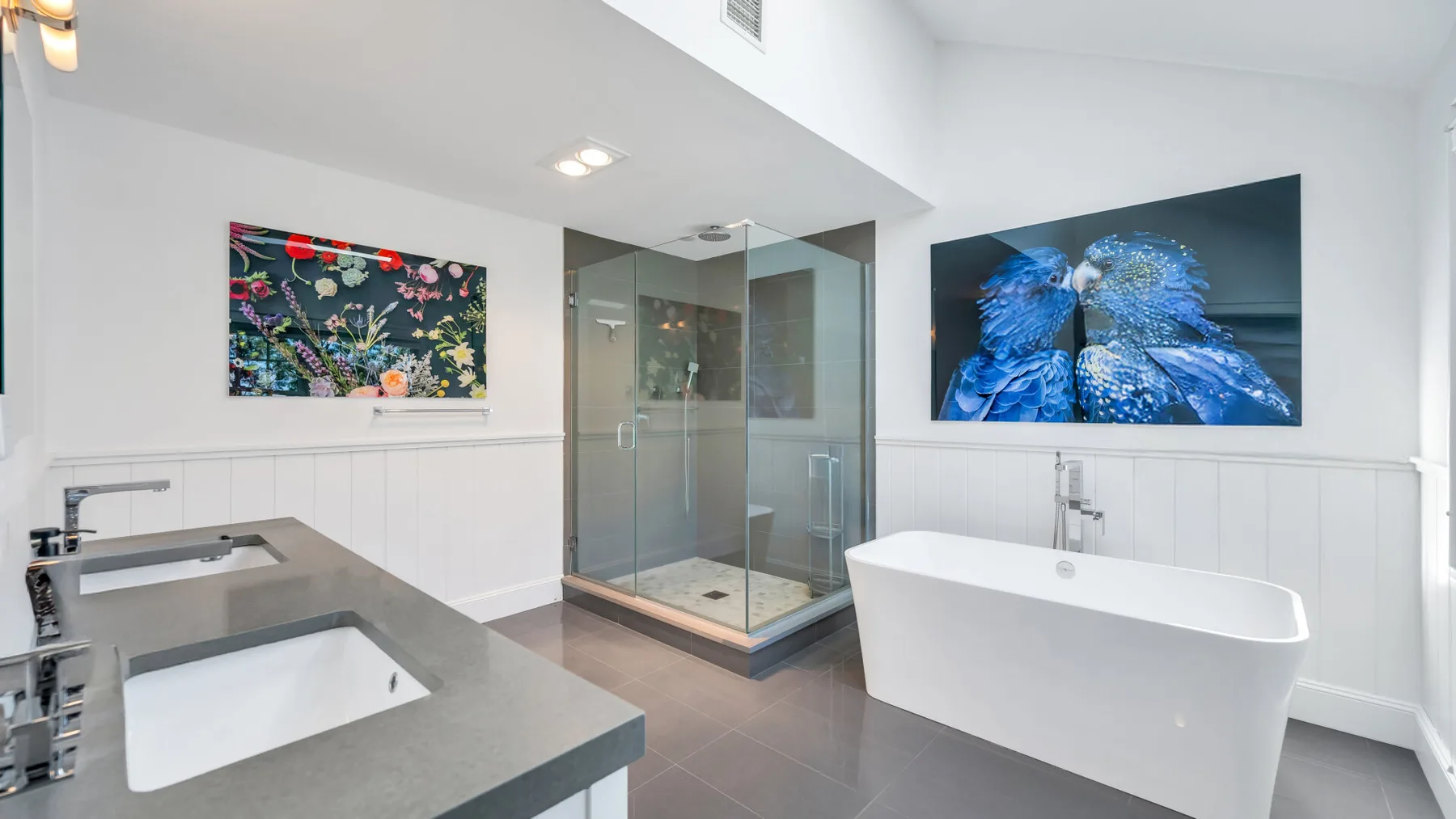 A bright bathroom with a glass shower, a bathtub, and a double-sink vanity.