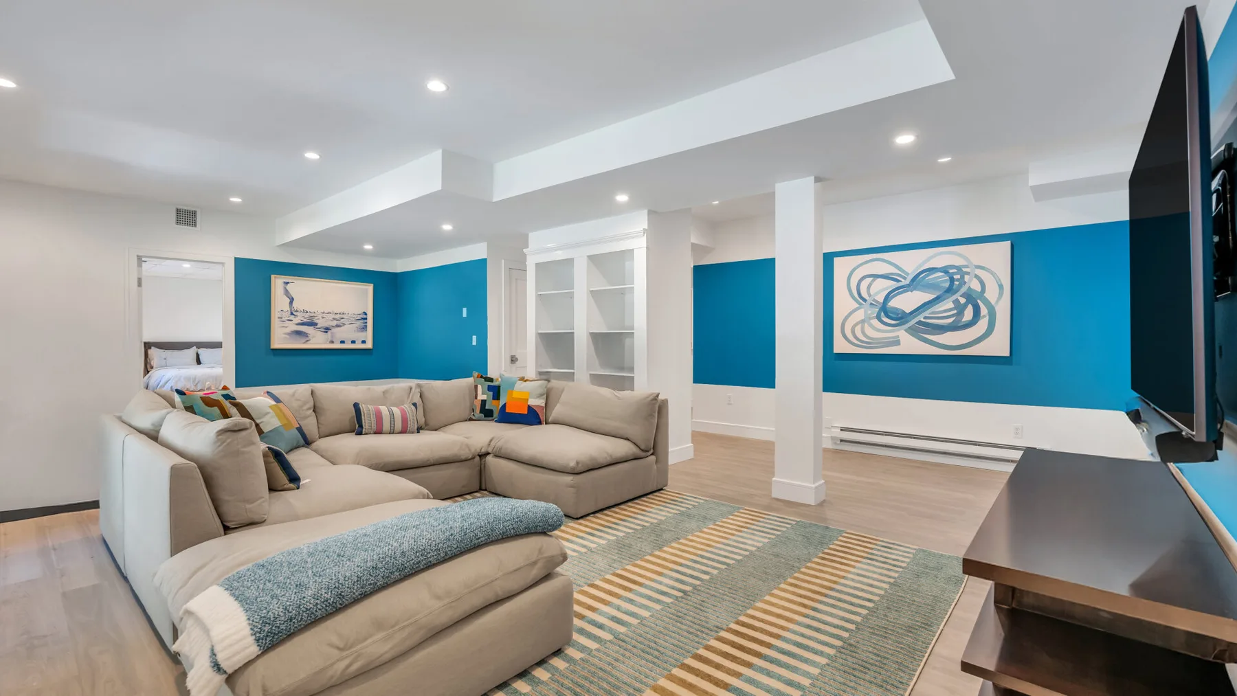 A basement living room with beige seating and blue accent walls.
