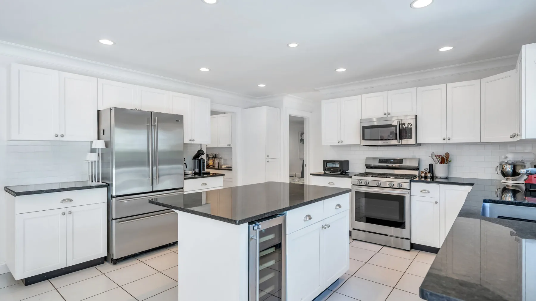 A bright kitchen with white cabinets, stainless steel appliances, and a central island.