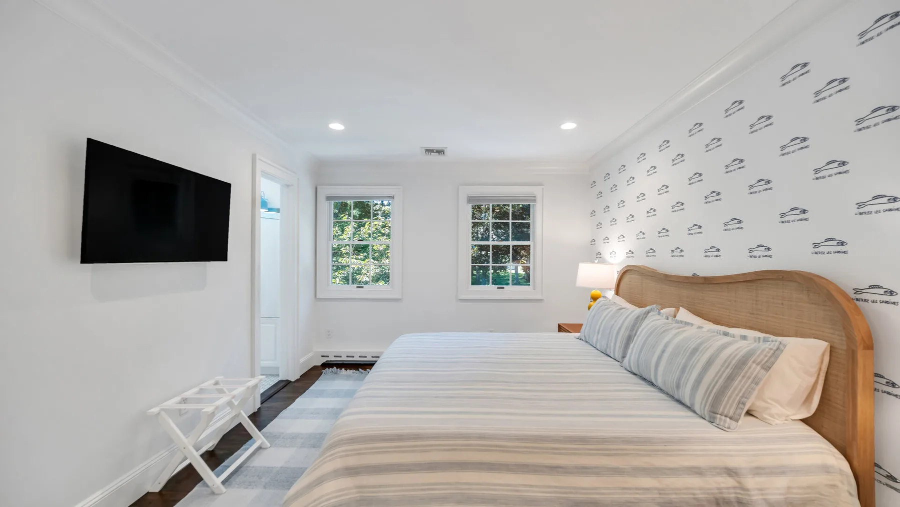 A bright bedroom with a large bed and a wall-mounted television.