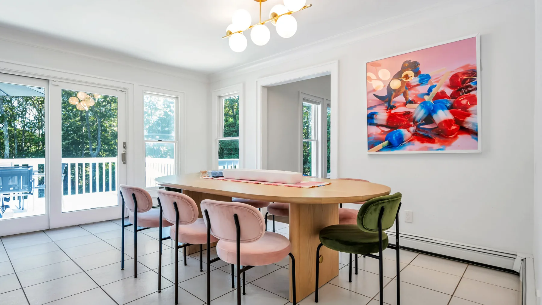 A bright dining area with a long table and colorful wall art.
