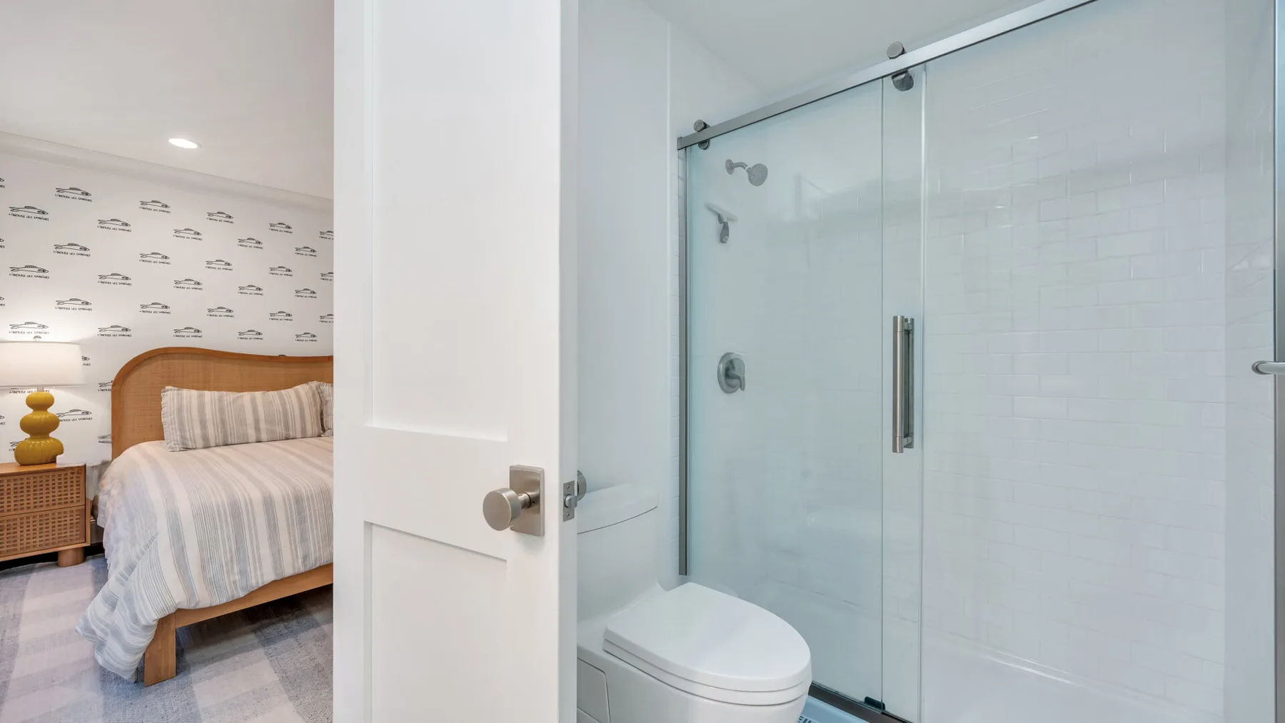 A bedroom and adjoining bathroom with a bed and glass shower.