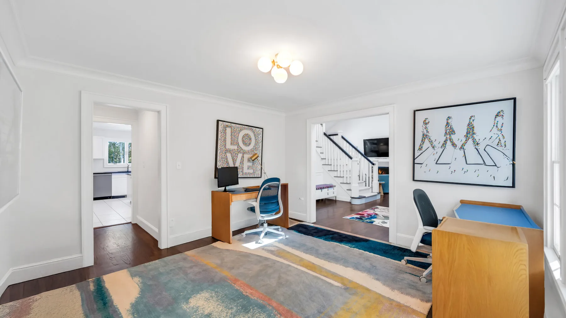 A bright interior room with a desk, seating, and colorful floor rugs.