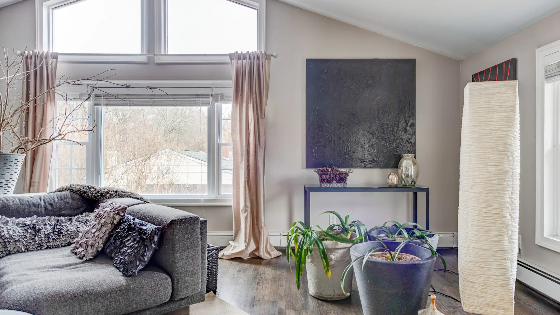 A bright living room with seating, plants, and large windows.