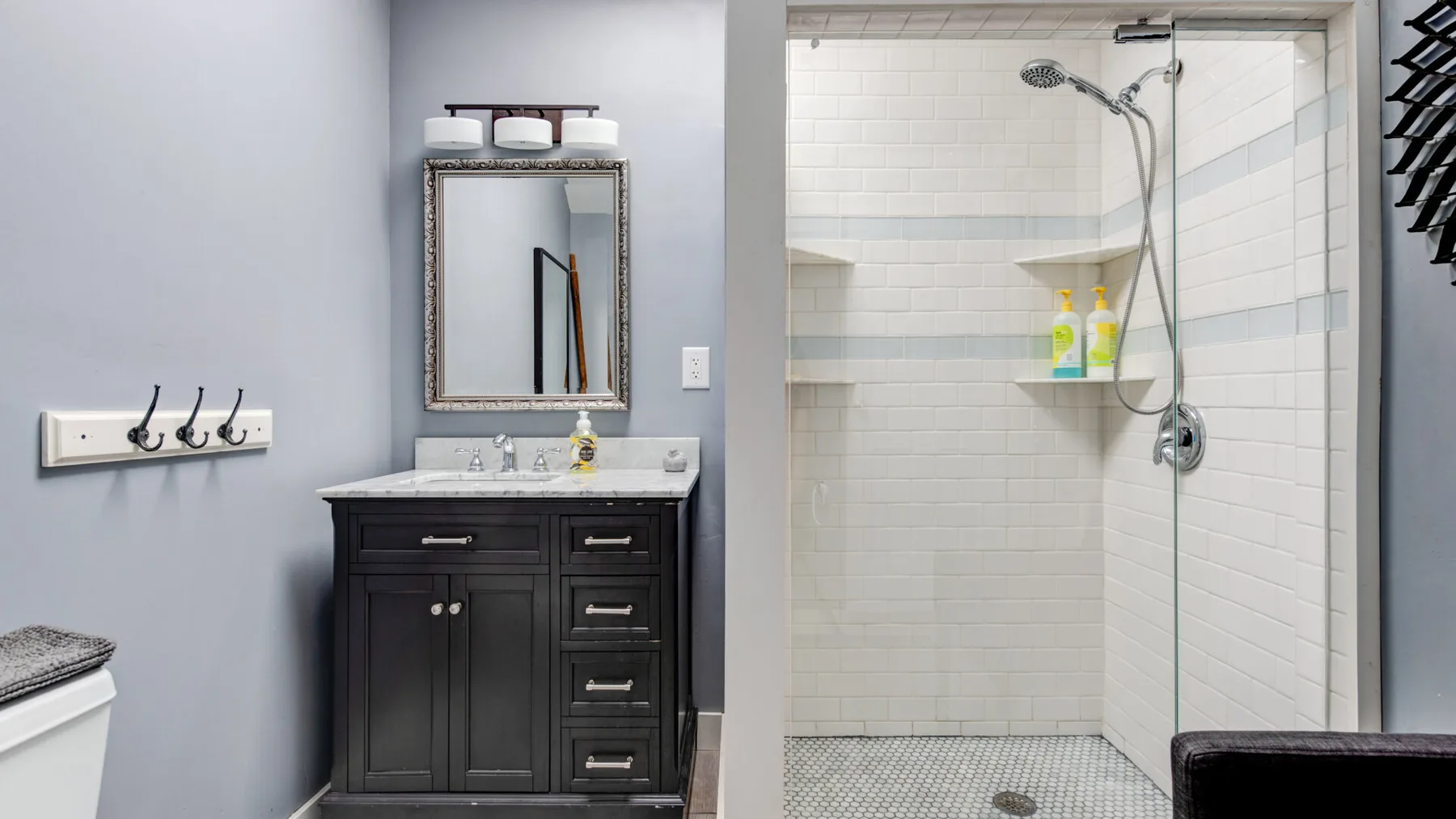 A bathroom with a dark vanity and a tiled shower.