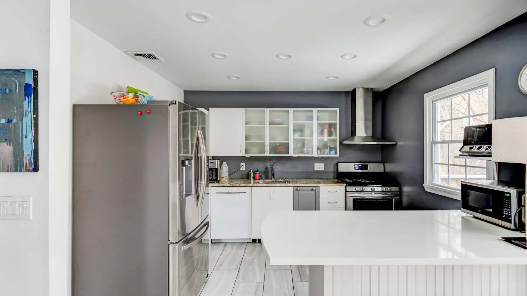 A bright kitchen with white cabinets, stainless steel appliances, and a central island.