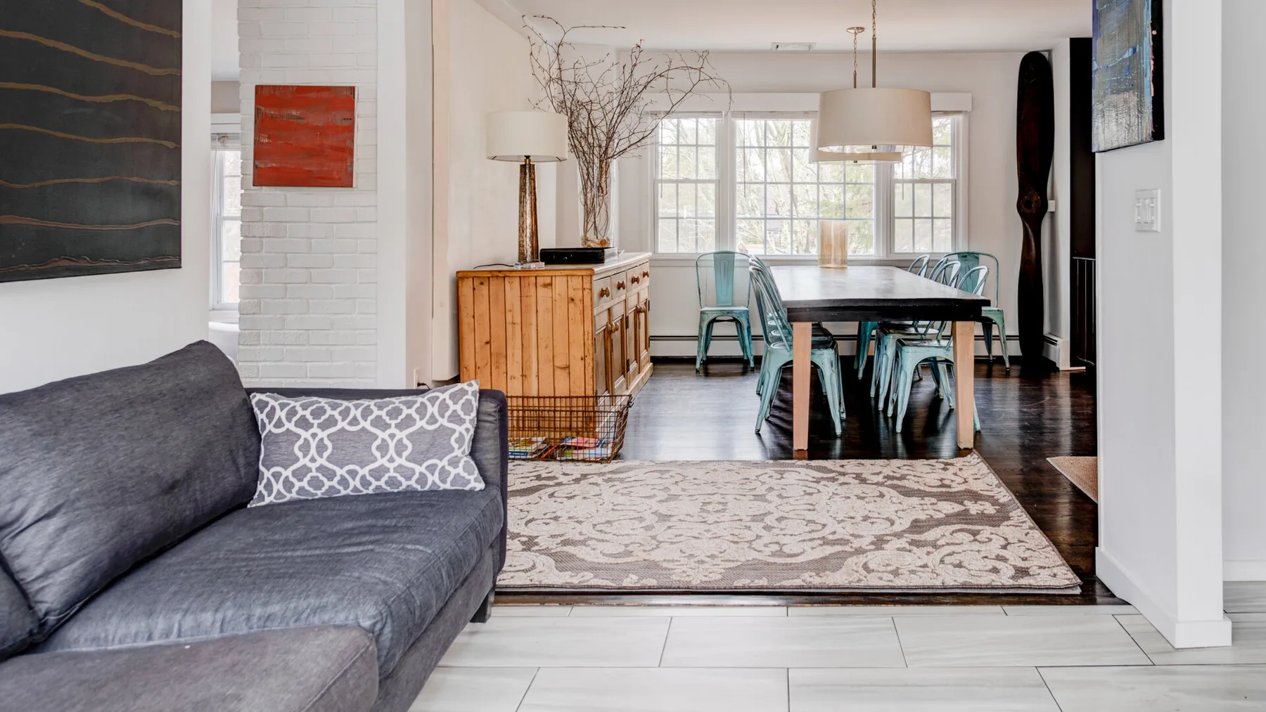 A living and dining area with a gray sofa beside a dining table.