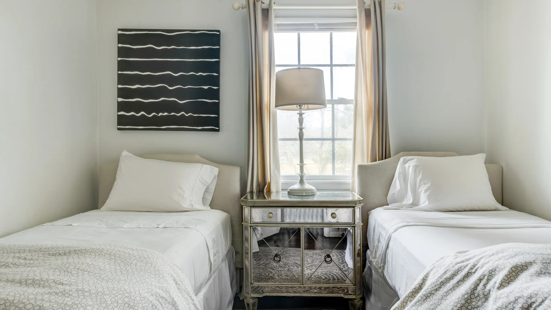 A bedroom with two single beds beside a window and a small bedside table.