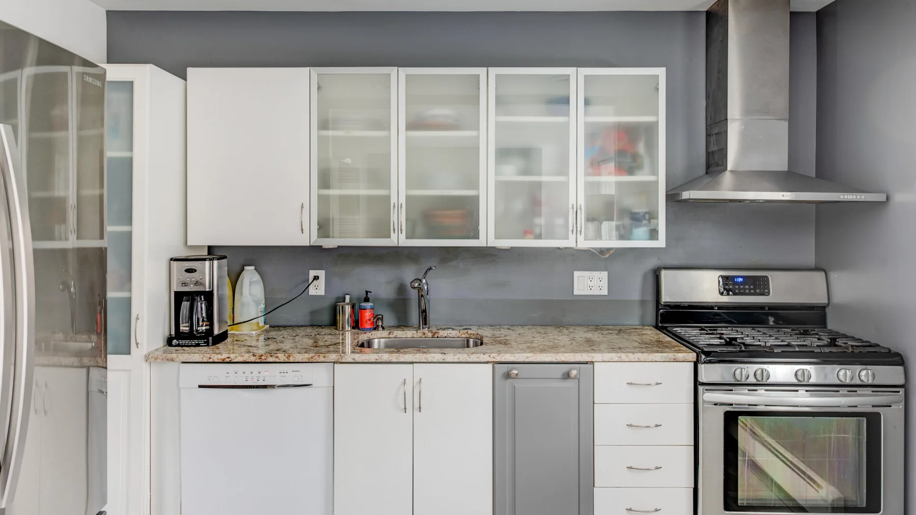 A modern kitchen with white cabinetry, a countertop, and a stainless-steel range.