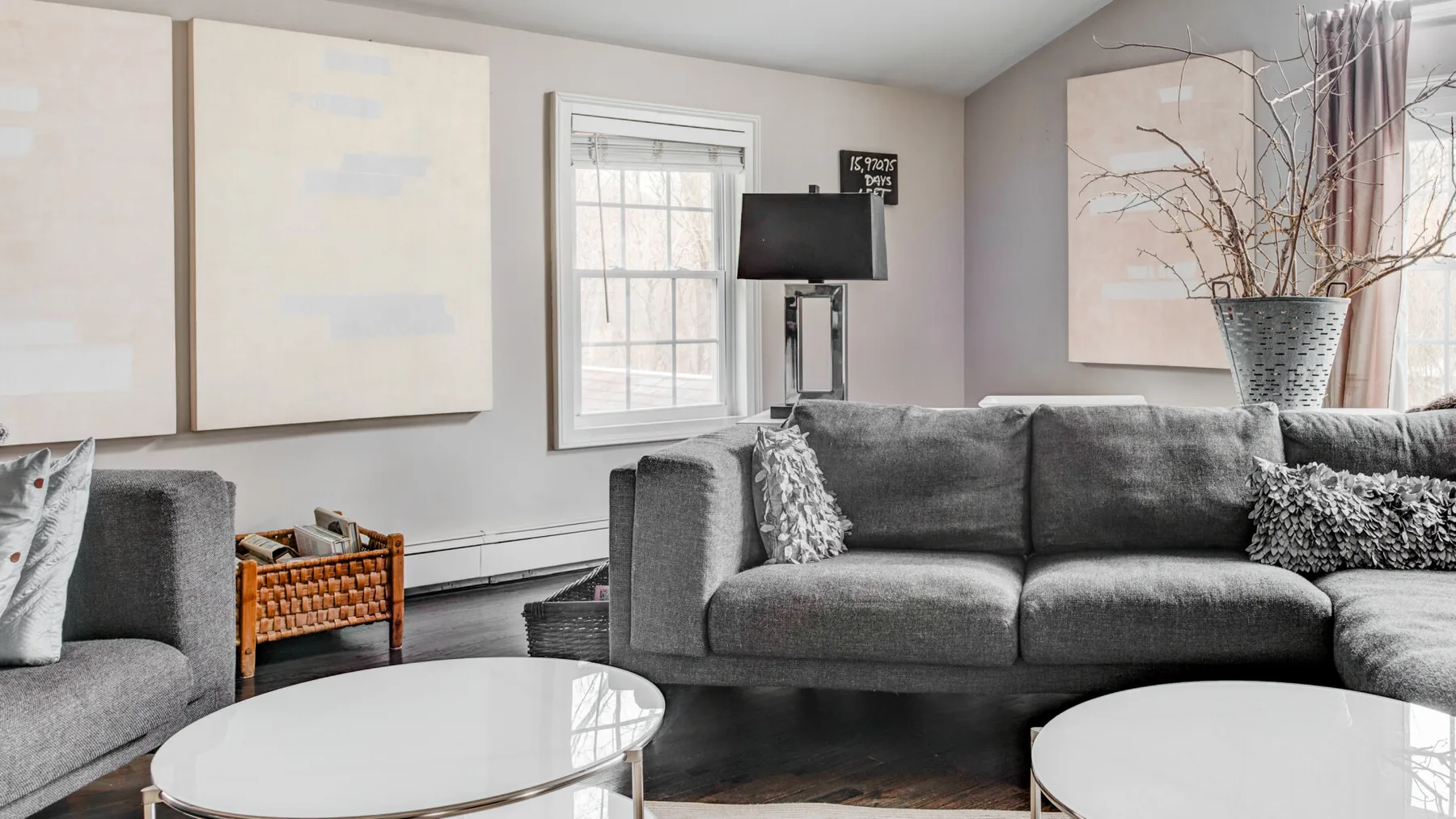 A living room with gray seating, round coffee tables, and wall art.