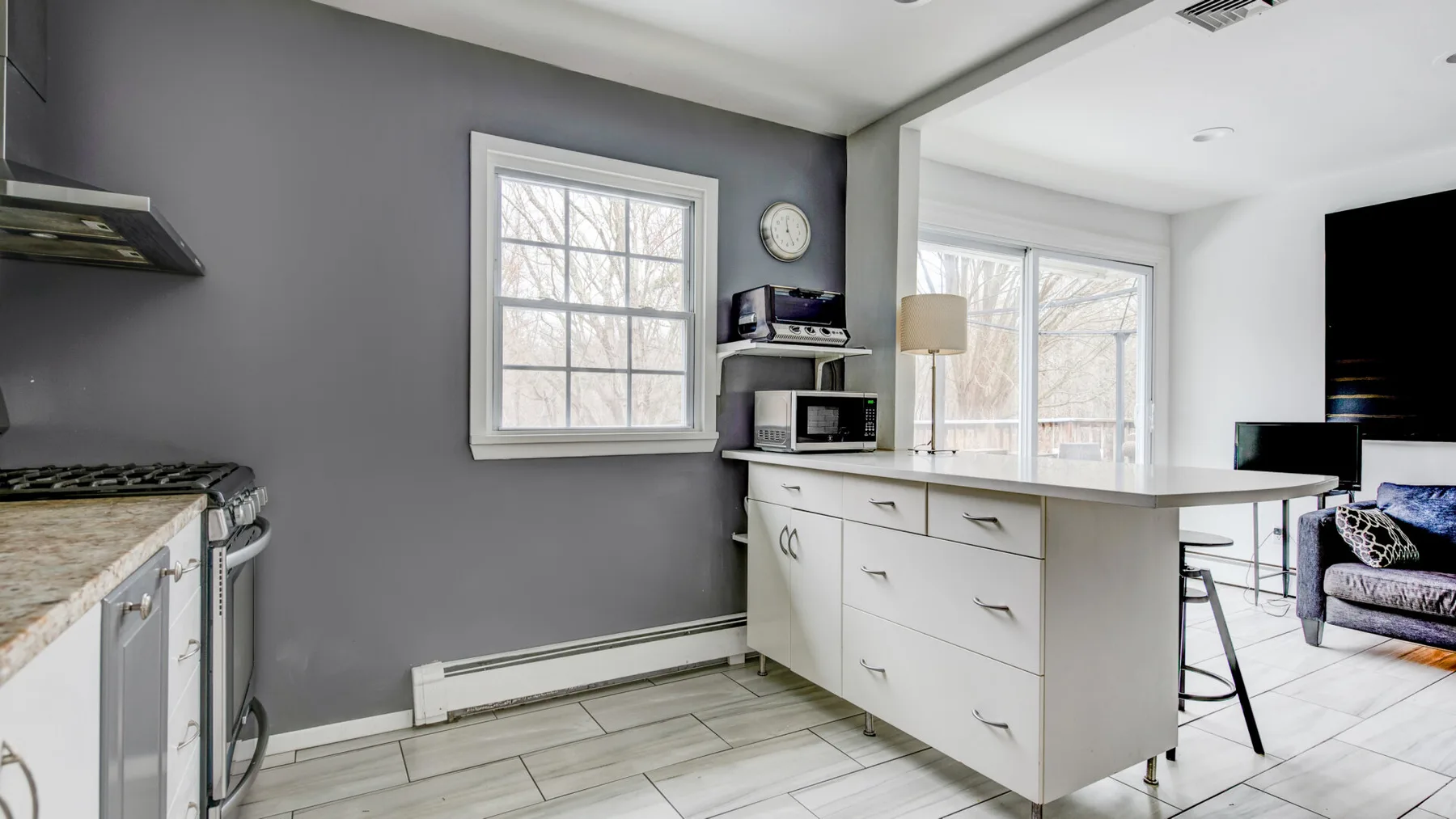 A kitchen with a central island and windows opening onto a bright living area.