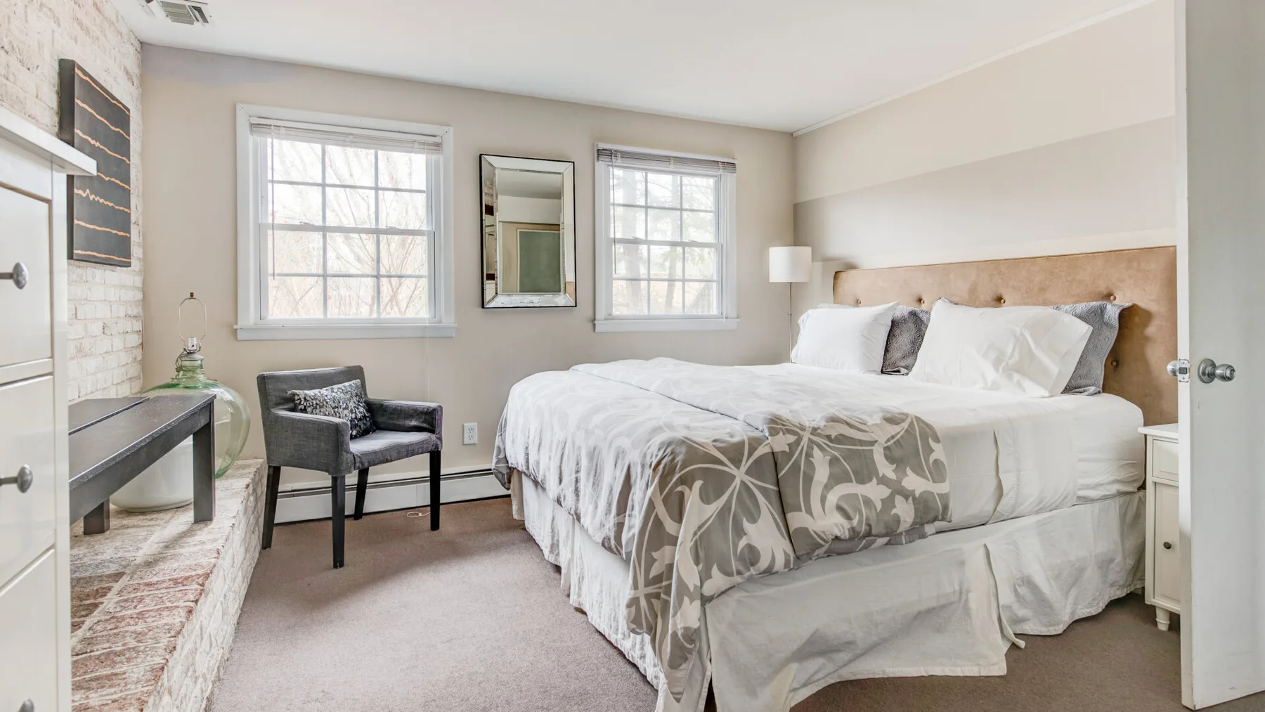 A bedroom with a large bed, two windows, and a small bedside lamp.
