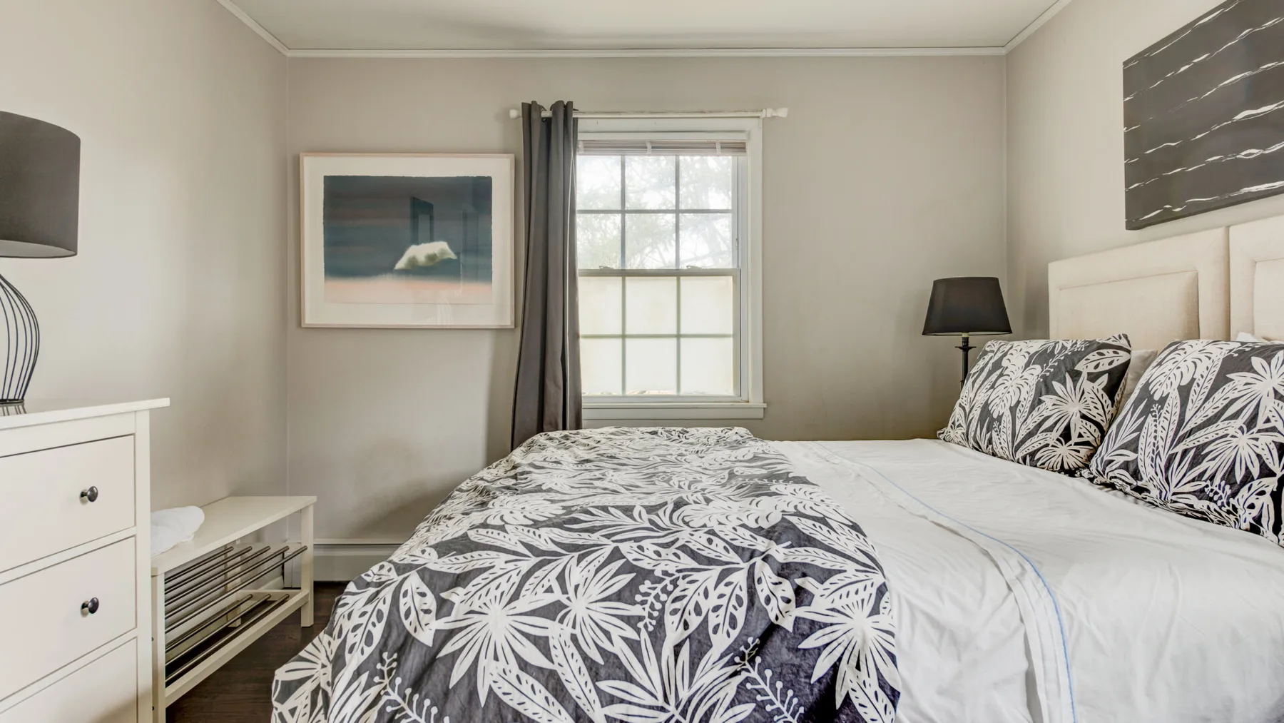 A bedroom with a bed covered by a black-and-white patterned blanket.