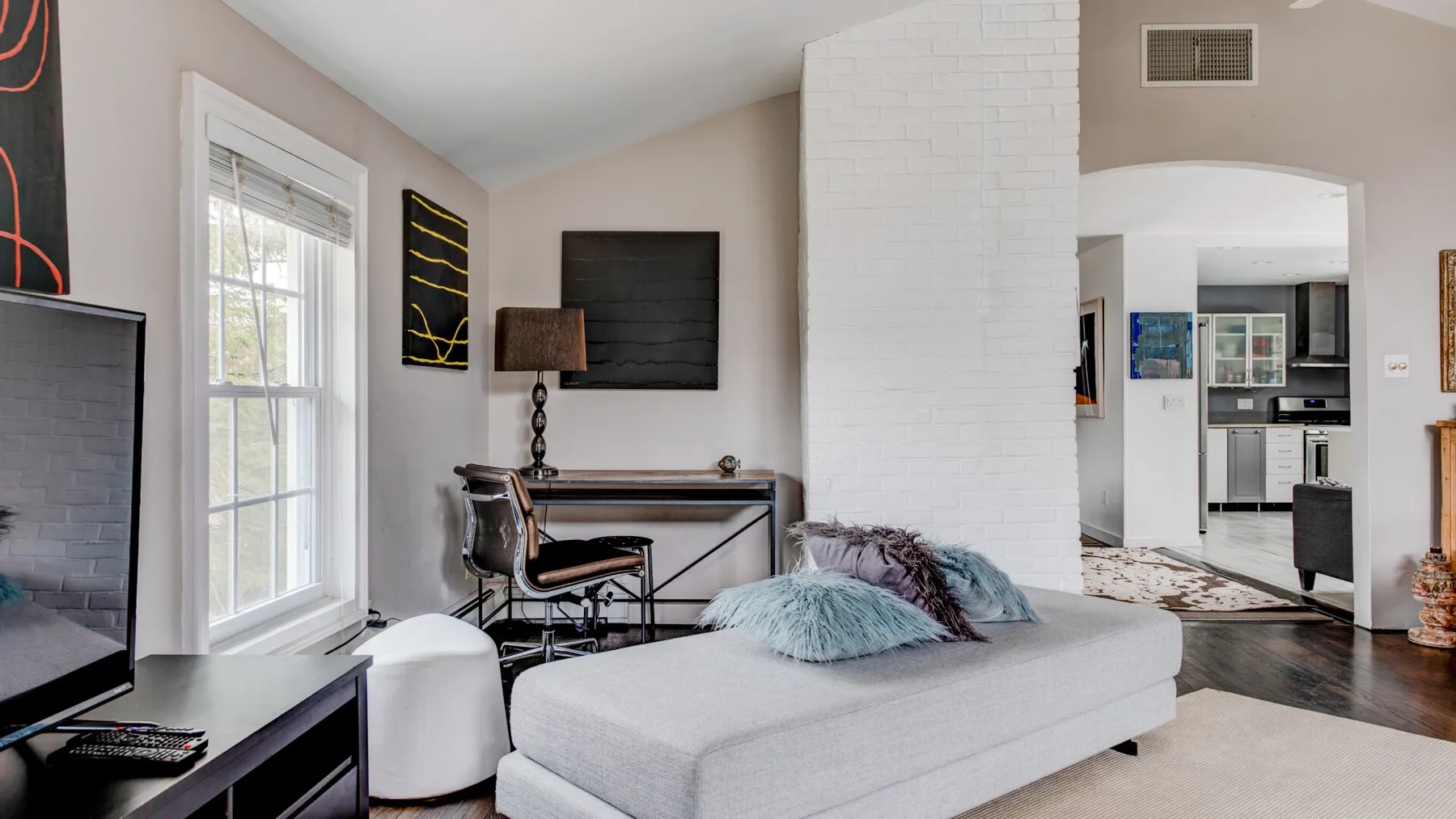 A living room with a low upholstered seating area and a television mounted on the wall.