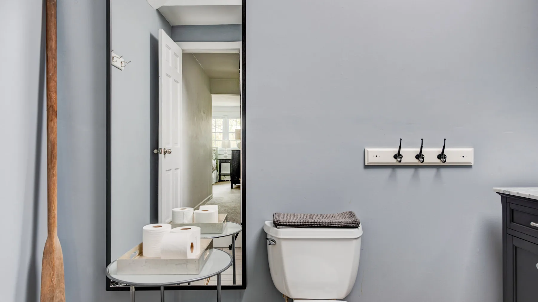 A bathroom with a toilet, sink, and wall-mounted hooks.