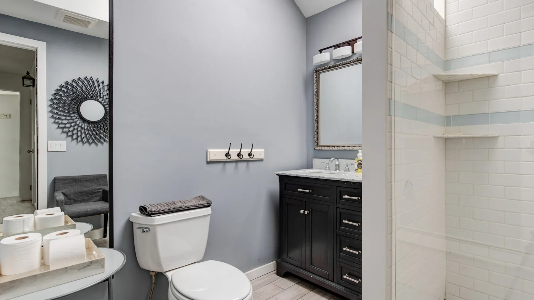 A bathroom with a toilet, dark vanity, and tiled shower area.