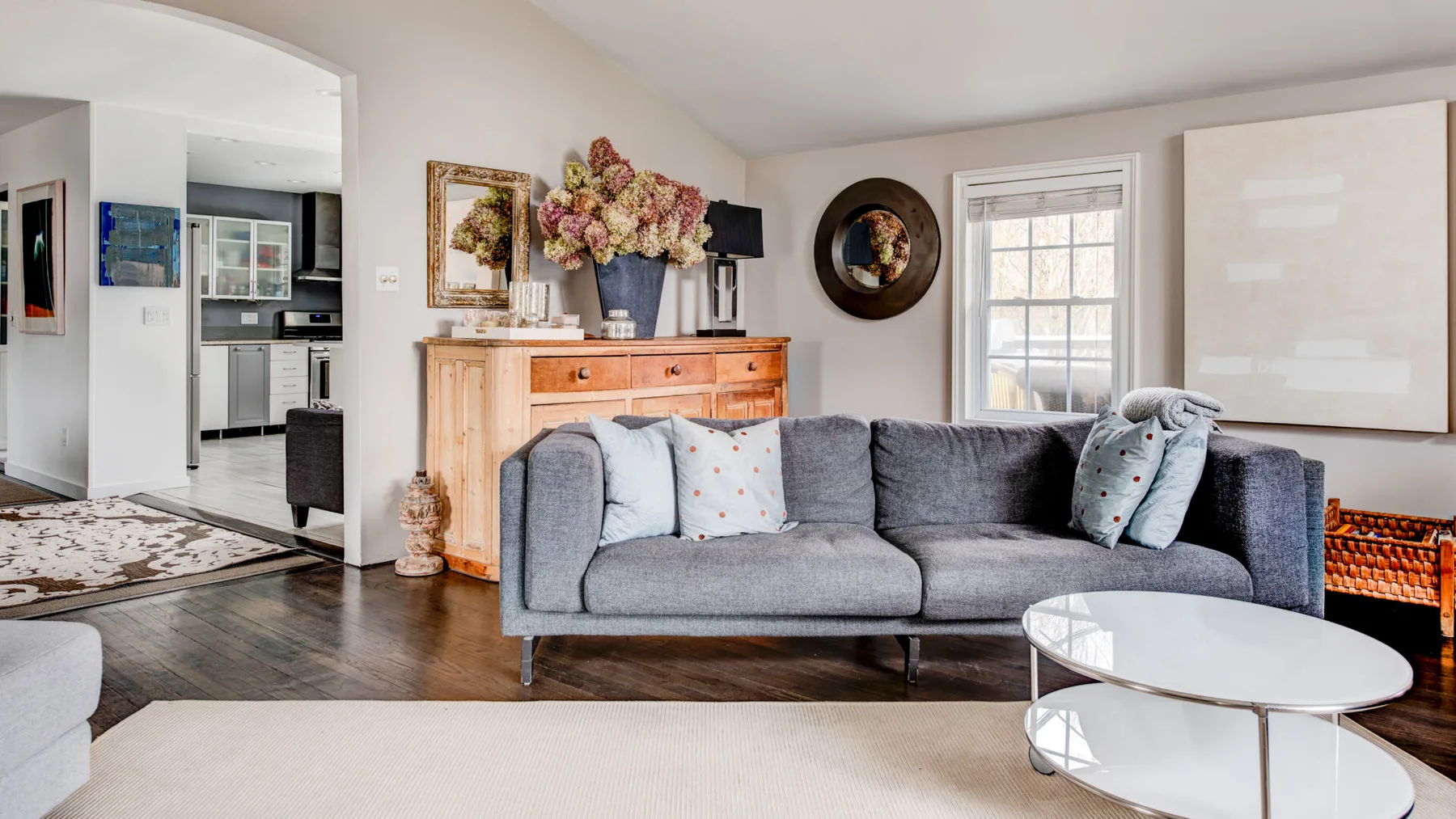 A bright living room with gray seating, a coffee table, and a fireplace.