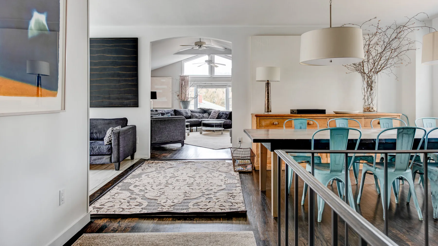 An open-plan living and dining area with a patterned rug and turquoise seating.