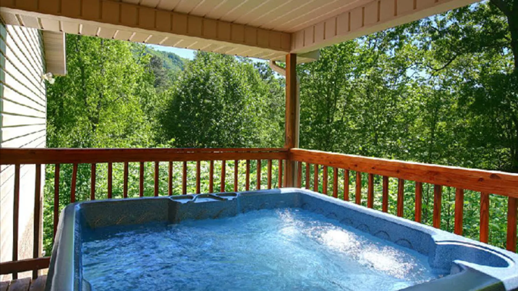 A covered outdoor hot tub overlooks a leafy wooded view.