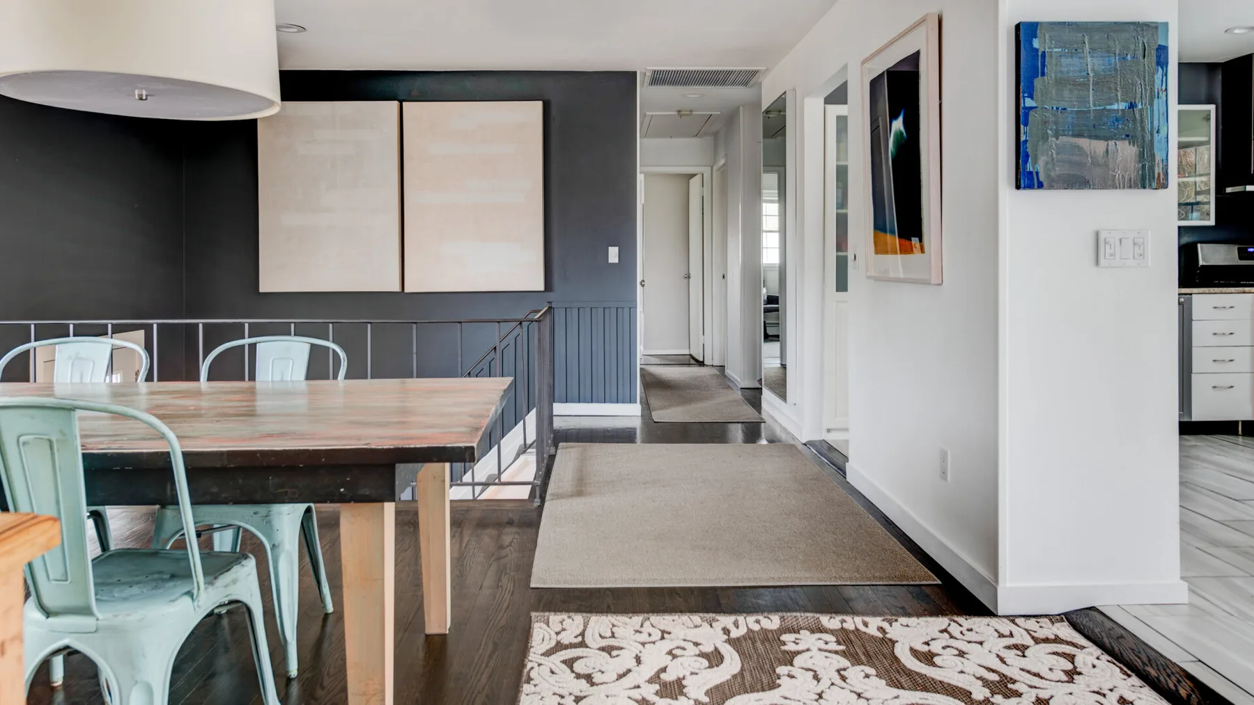 A dining area with a wooden table and chairs beside a hallway.