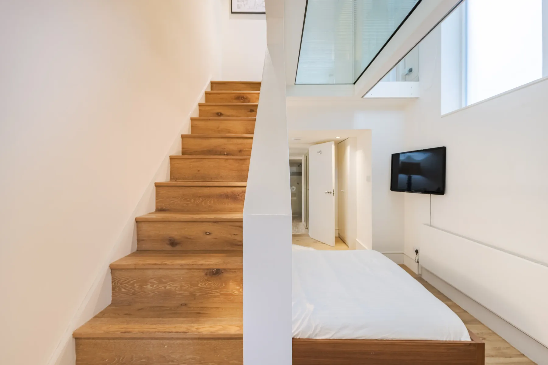 Interior stairway beside a sleeping area with a wall-mounted television.