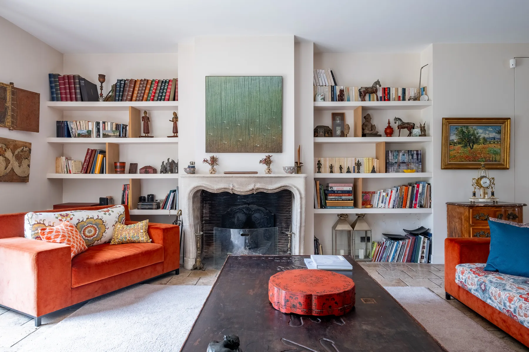 Sala de estar con chimenea, estanterías y asientos alrededor de una mesa baja.