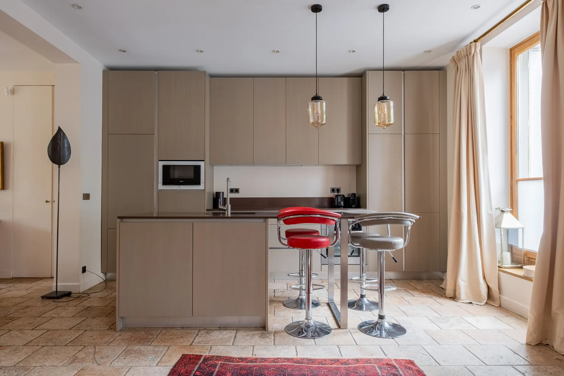 Una cocina moderna con una isla central y dos taburetes.
