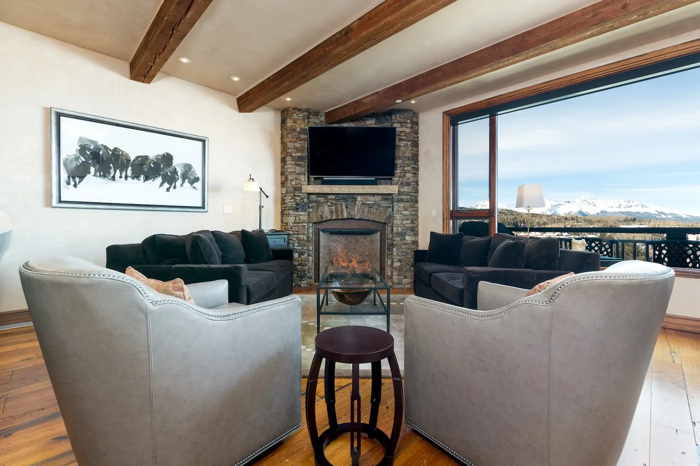 A living room with seating arranged around a stone fireplace and television.