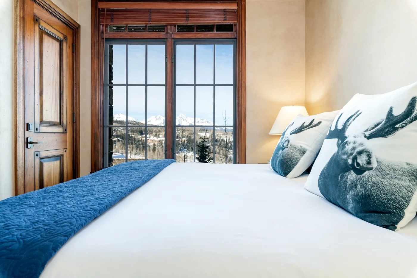 A bedroom with a bed beside large windows overlooking a snowy landscape.