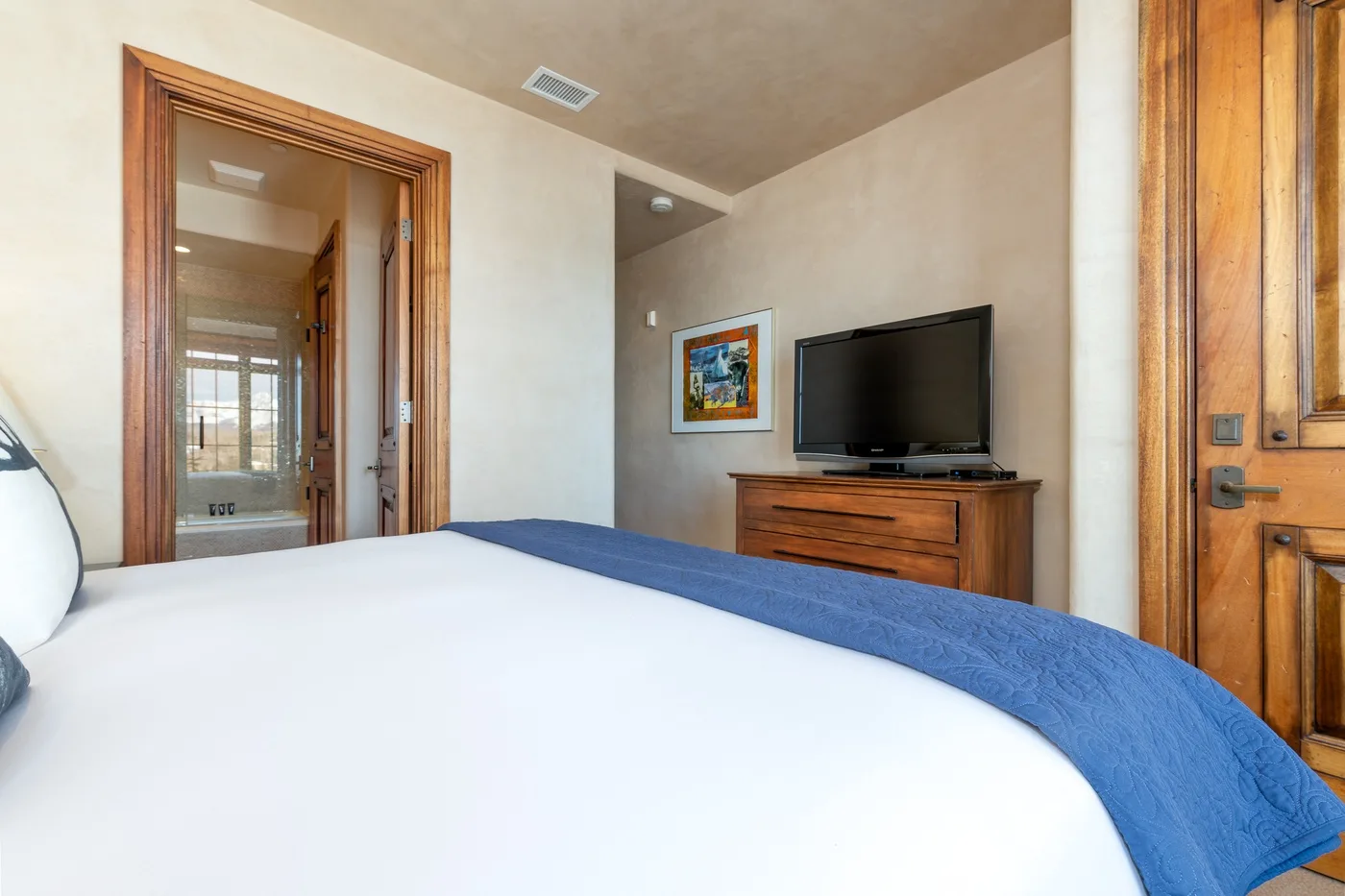 A bedroom with a bed, television, and wooden dresser.