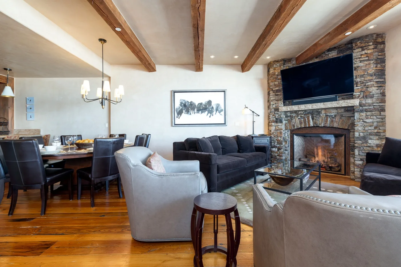 Una sala de estar y comedor con asientos, una chimenea y vigas expuestas en el techo.