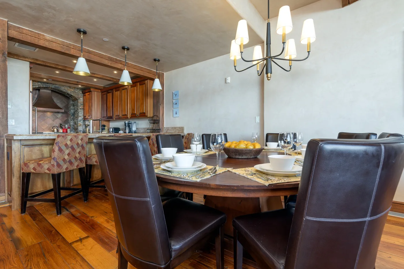 Comedor con una mesa puesta y asientos tapizados oscuros.