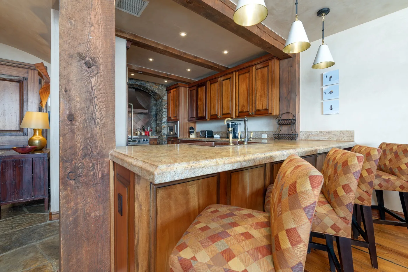 A warm-toned kitchen with a stone island and cushioned seating.