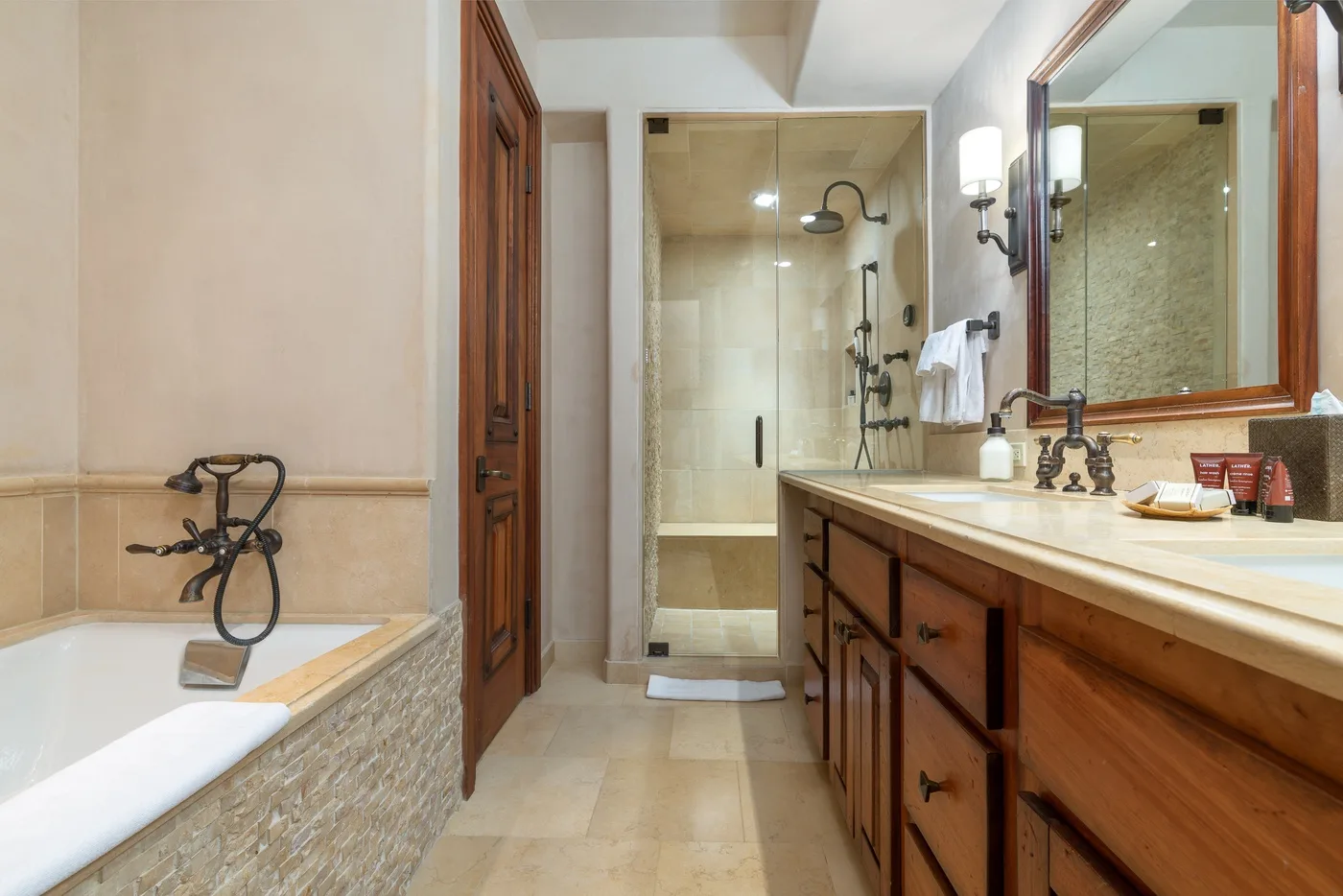 A bathroom with a bathtub, glass shower, and long vanity.