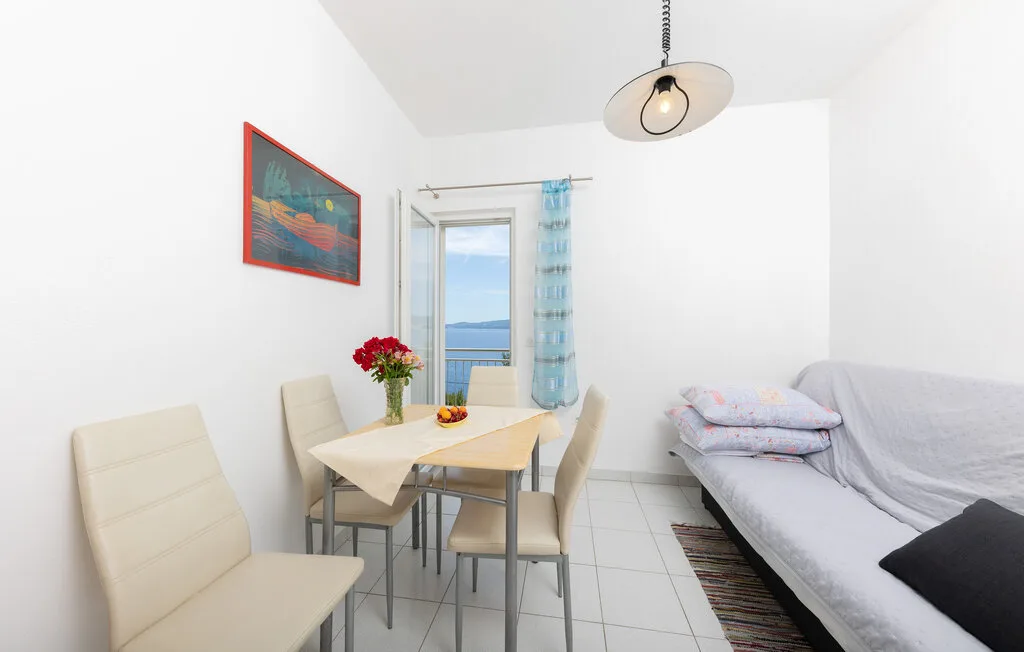 A bright dining and sitting area has a table beside a large window.