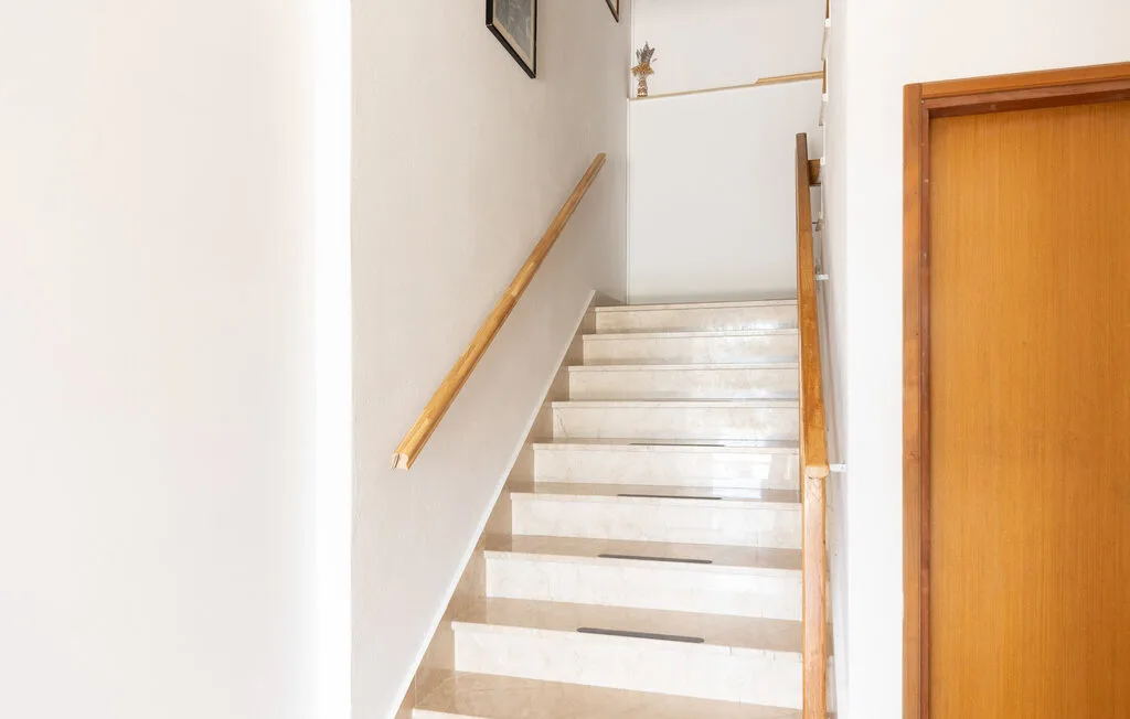 Una escalera interior con peldaños claros y pasamanos de madera.