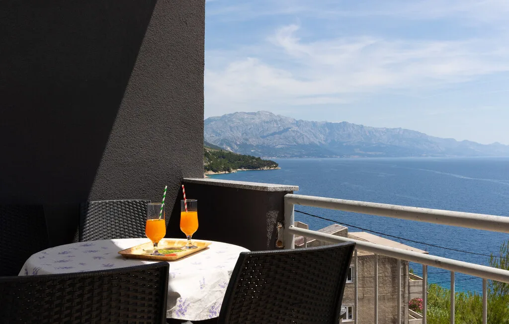 Una zona de comedor en el balcón da al mar y a montañas lejanas.