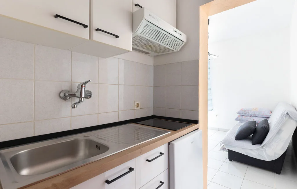 Una cocina compacta con fregadero de acero inoxidable y vista a una habitación contigua luminosa.