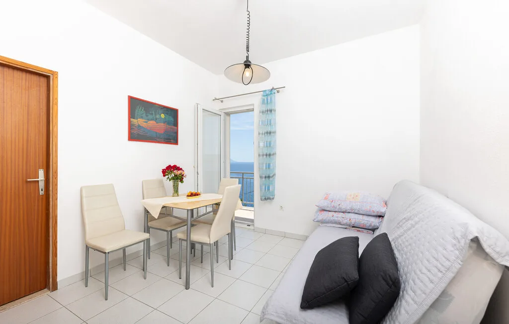 Una habitación luminosa con mesa de comedor, asientos y una cama junto a la ventana.