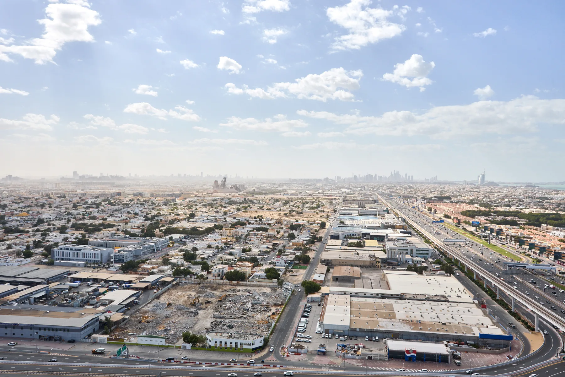 Aerial view of a sprawling city with a multilane highway beneath a partly cloudy sky.