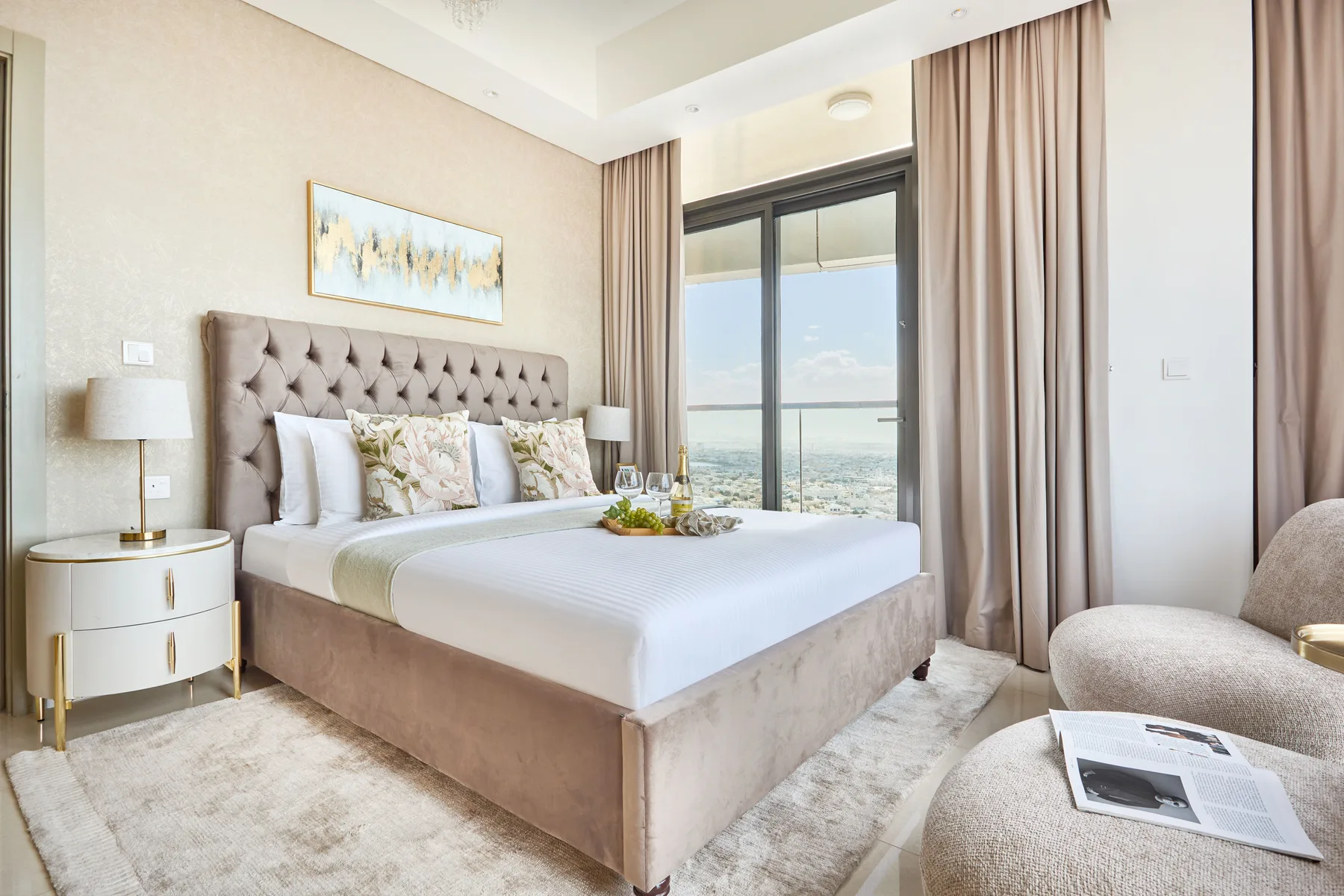A bright bedroom with a large bed beside a floor-to-ceiling window.