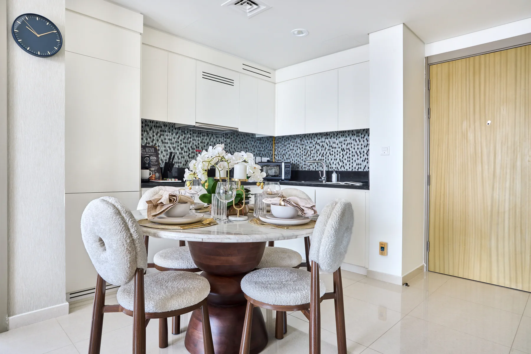 A dining area with a round table set beside a bright kitchen.