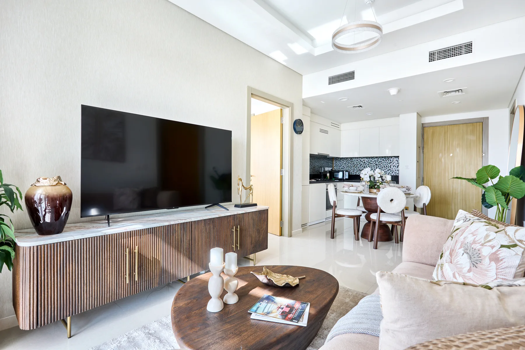 A bright living room with a television, seating, and a dining area.